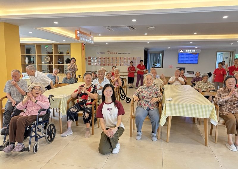 Yanzi kneeling at the front of a large group of residents and staff for a photo